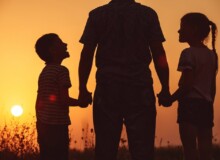 Father and children standing in the park at the sunset time.